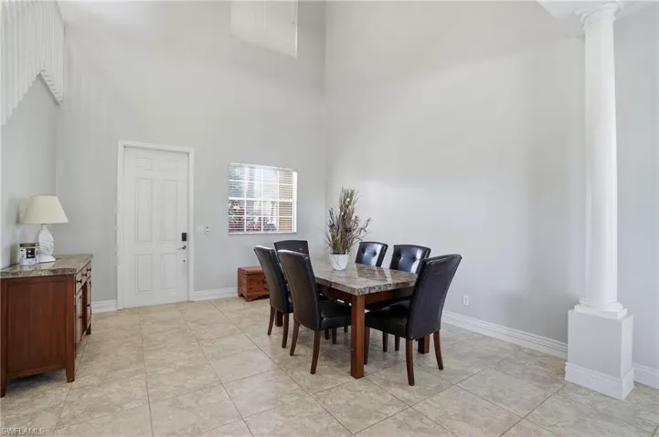 Dining area featuring a towering ceiling, decorative columns, and light tile patterned floors