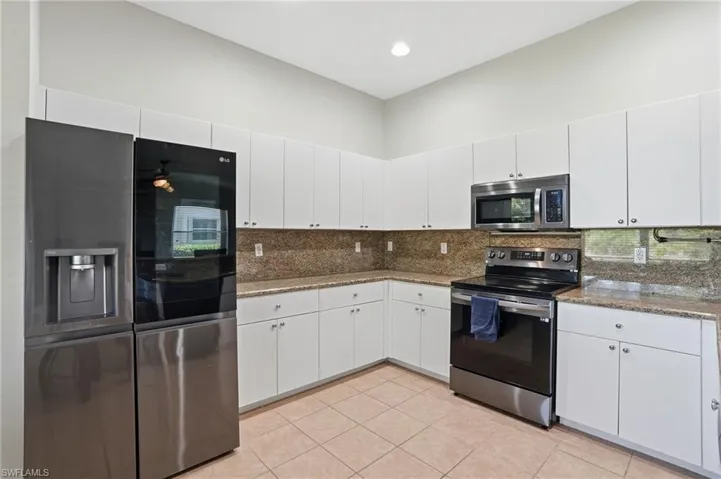 Kitchen with stainless steel appliances, tasteful backsplash, white cabinets, dark stone countertops, and recessed lighting