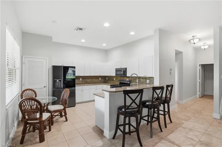 Kitchen featuring decorative backsplash, a peninsula, white cabinets, a breakfast bar, and appliances with stainless steel finishes