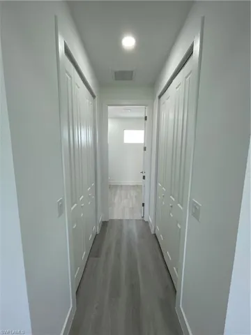 Corridor featuring dark wood-style flooring and baseboards