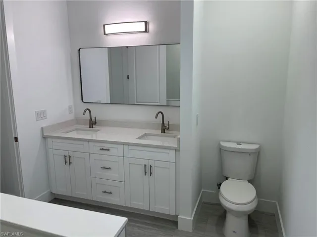 Bathroom featuring double vanity and dark wood finished floors