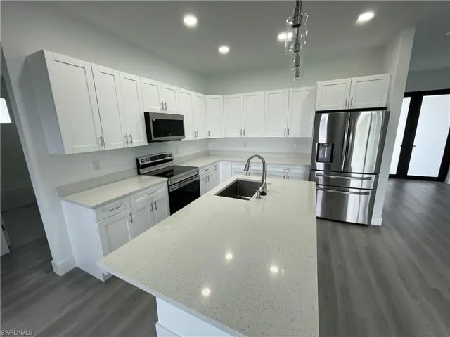 Kitchen featuring appliances with stainless steel finishes, white cabinetry, an island with sink, and recessed lighting