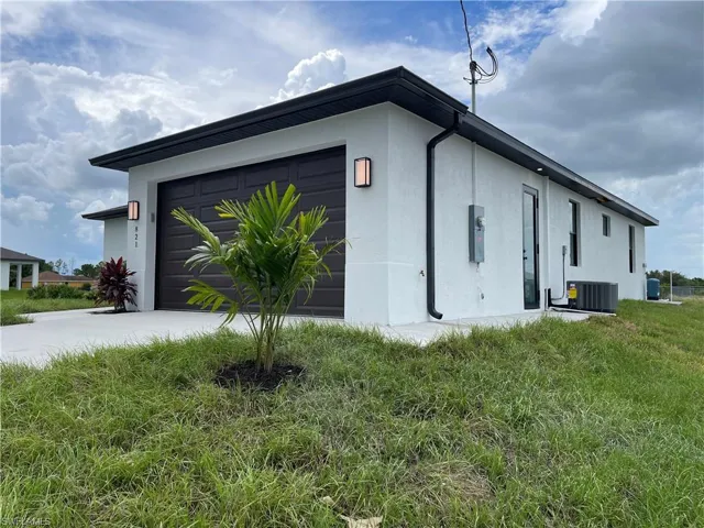 View of side of property featuring stucco siding, driveway, an attached garage, and a lawn