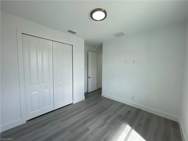 Unfurnished bedroom featuring dark wood-type flooring and a closet