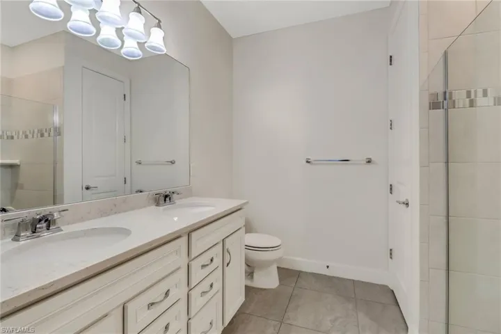Master bath with tile patterned flooring, a sink, toilet, and double vanity