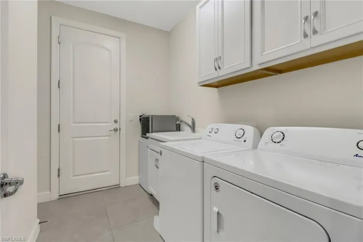 Laundry area with cabinet space, washer and dryer, and light tile patterned flooring