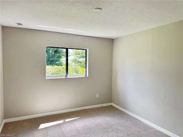 Guest bedroom 1 with a textured ceiling and carpet floors
