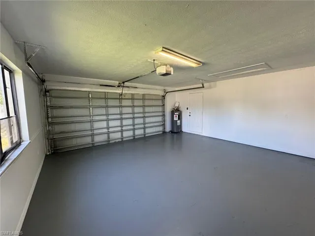 Garage featuring electric water heater and a garage door opener