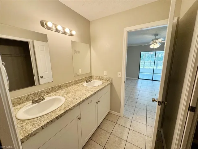 Master bathroom featuring tile patterned floors, ceiling fan, vanity, and a textured ceiling