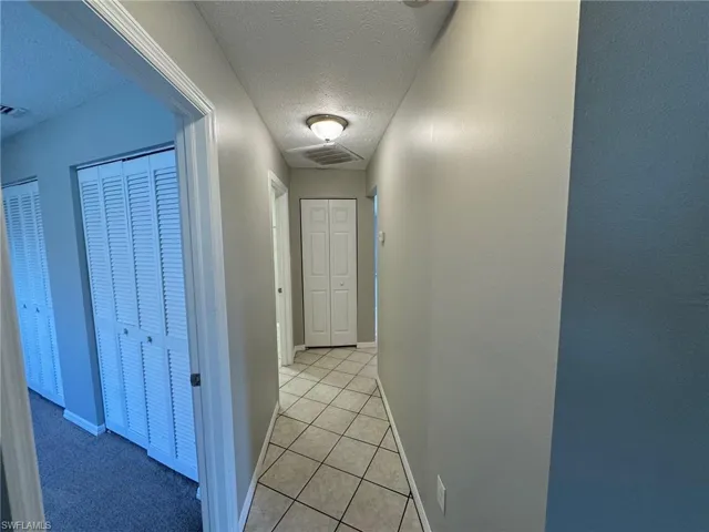 Hall featuring light tile patterned floors and a textured ceiling