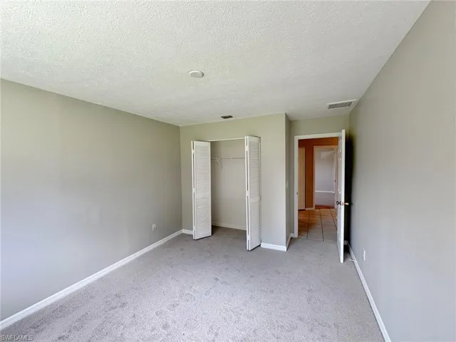 Guest bedroom 1featuring light carpet, a textured ceiling, and a closet