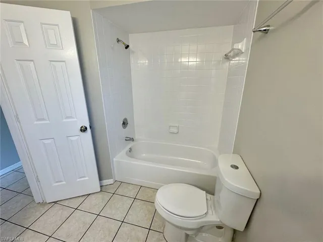 Bathroom featuring tile patterned floors, tiled shower / bath combo, and toilet