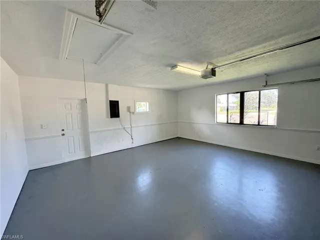 Garage featuring electric panel and a garage door opener