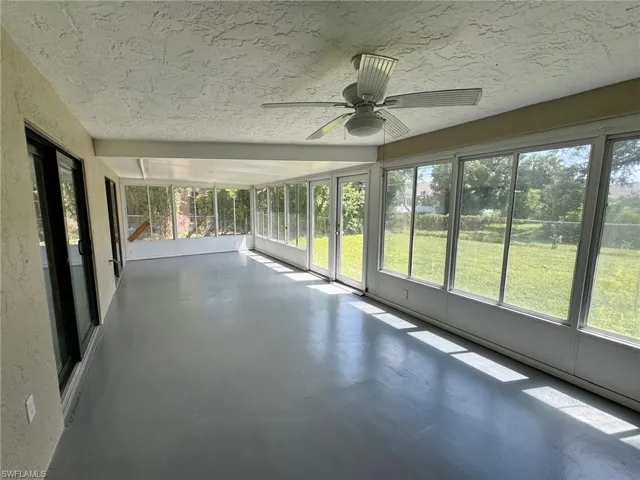 Unfurnished sunroom featuring a wealth of natural light and ceiling fan