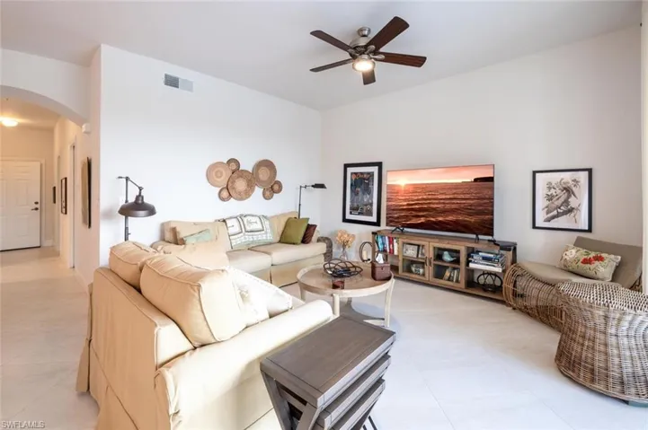 Living room featuring arched walkways, a ceiling fan, and light tile patterned flooring