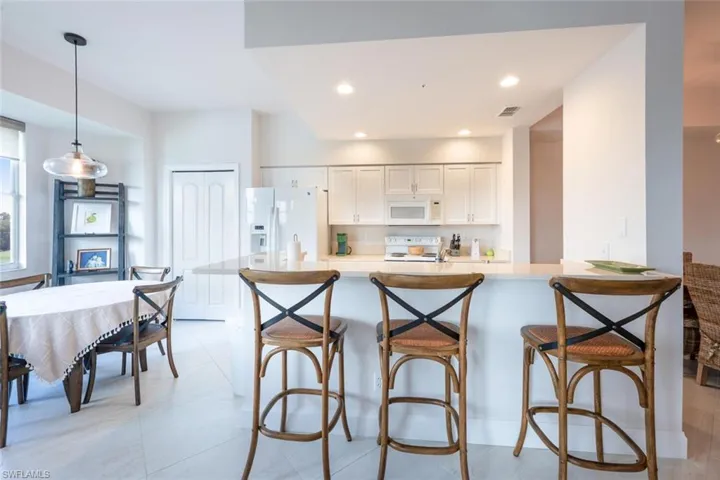 Kitchen featuring a breakfast bar, white cabinetry, white appliances, recessed lighting, and hanging light fixtures