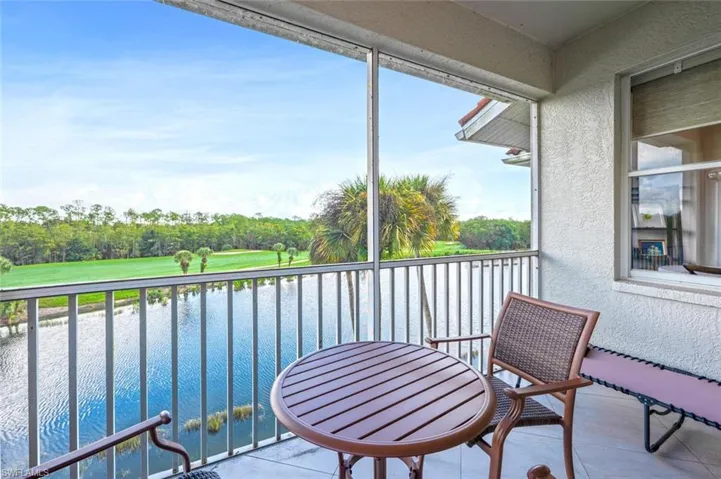 Balcony featuring a sunroom, view of scattered trees, golf course view, and a water view