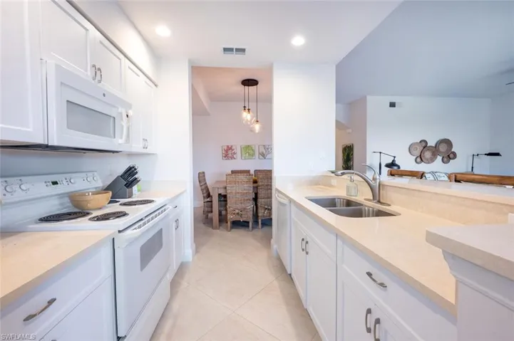 Kitchen with white appliances, white cabinetry, pendant lighting, light tile patterned floors, and recessed lighting