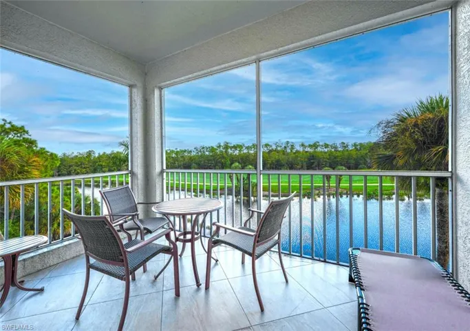Sunroom featuring view of scattered trees, a water view, and healthy amount of natural light