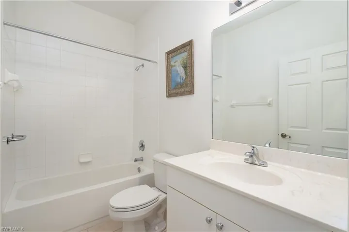 Full bathroom with tile floors, tiled shower / bath, oversized vanity, and toilet