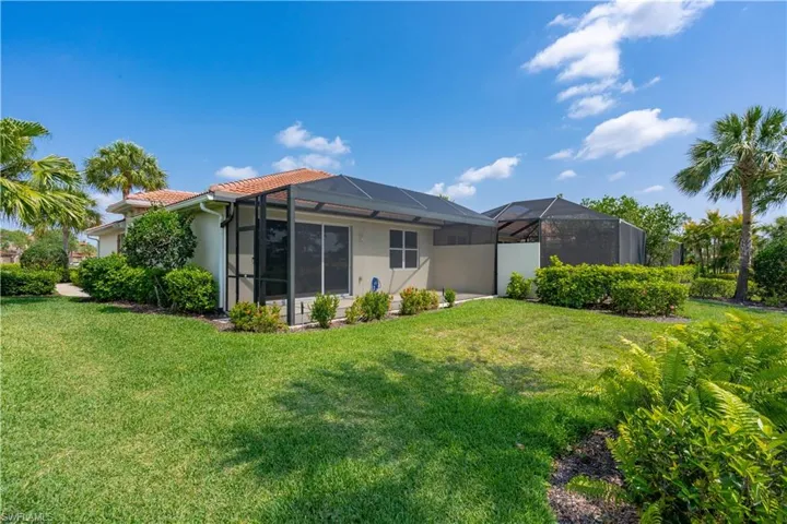 Rear view of house with glass enclosure and a lawn