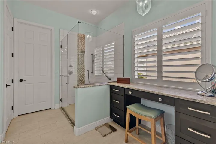 Bathroom with vanity, a shower with shower door, and tile patterned flooring