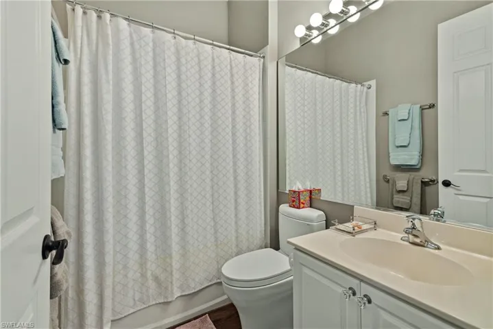 Full bathroom with shower / tub combo with curtain, vanity, hardwood / wood-style flooring, and toilet