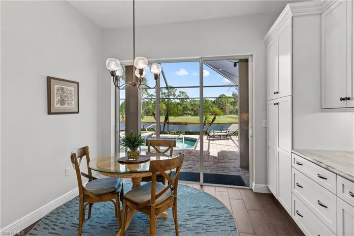 Dining room with a water view, dark hardwood / wood-style floors, and an inviting chandelier