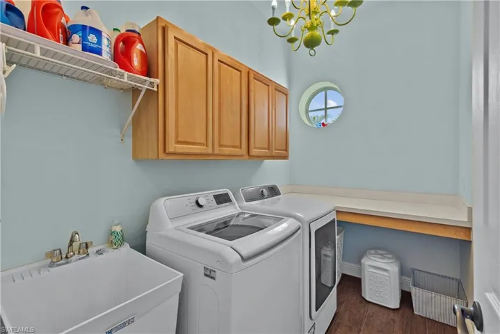 Laundry room featuring cabinets, a chandelier, separate washer and dryer, dark wood-type flooring, and sink