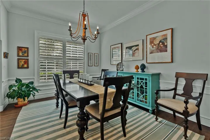 Dining space featuring a notable chandelier, dark wood-type flooring, and crown molding