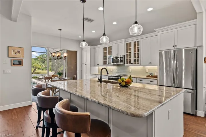 Kitchen with dark wood-type flooring, an island with sink, stainless steel appliances, and white cabinets