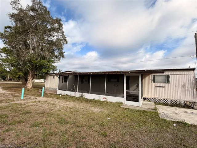 Back of property featuring a sunroom and a yard