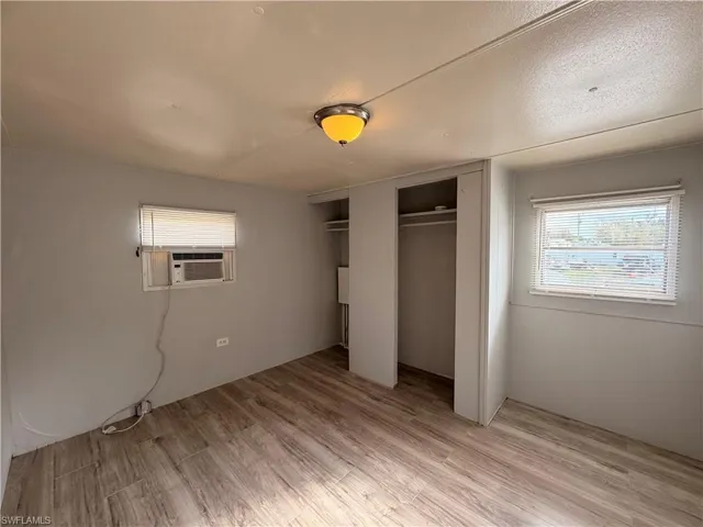Unfurnished bedroom with light wood-type flooring and cooling unit