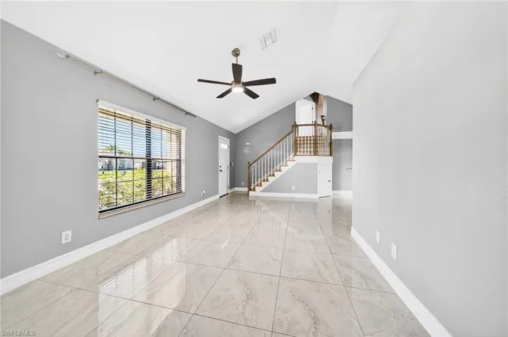 Unfurnished living room featuring a ceiling fan, lofted ceiling, and light marble finish flooring