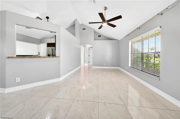 Empty room with arched walkways, a ceiling fan, and vaulted ceiling