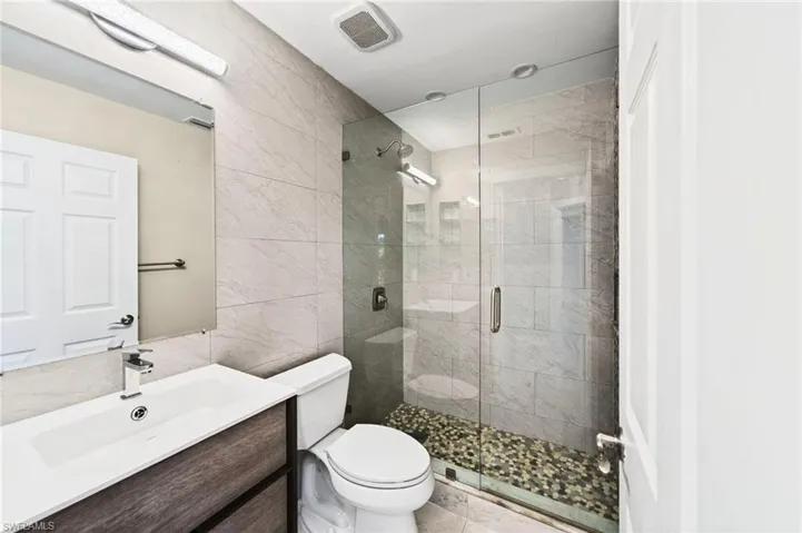 Bathroom with vanity, tile walls, and a shower stall