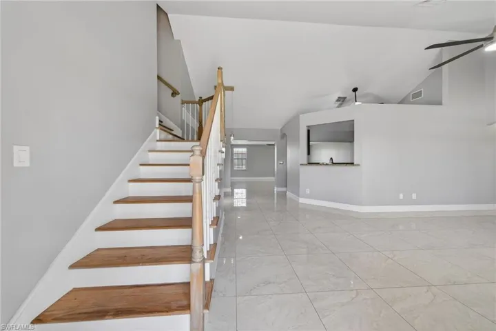 Staircase with ceiling fan and a high ceiling
