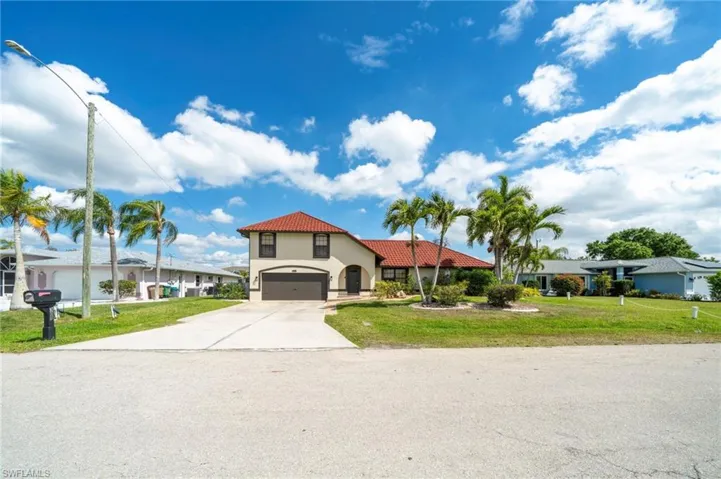 Mediterranean / spanish house featuring a front yard, concrete driveway, a tile roof, stucco siding, and an attached garage