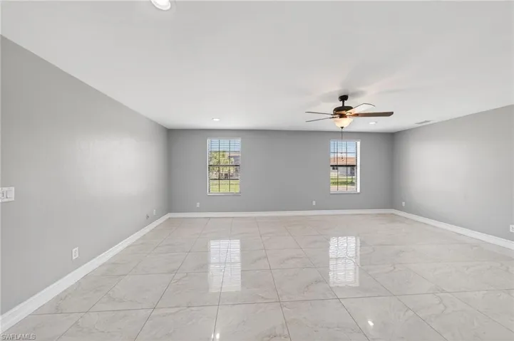 Empty room featuring a ceiling fan and light marble finish floors