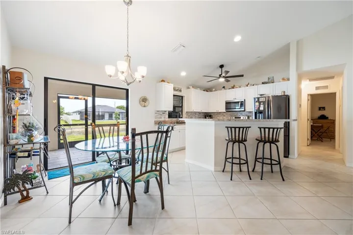 Open-concept kitchen and dining area featuring light-toned tile flooring, white cabinetry, and stainless-steel appliances