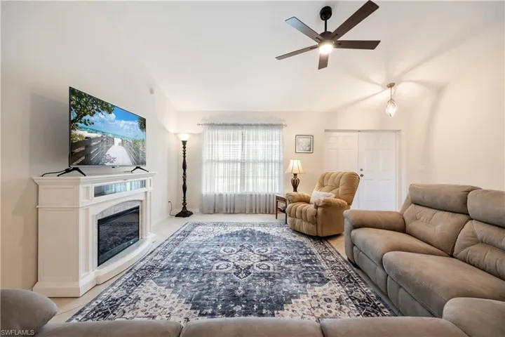 Living area featuring light-toned walls, tile flooring, and a white electric fireplace