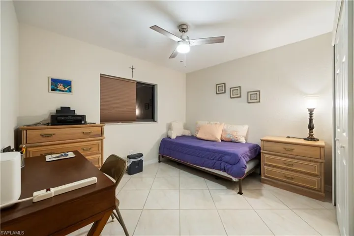 Bright room featuring a window with integrated blinds, a ceiling fan with light fixture, tile flooring, and white walls