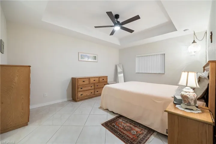 Bedroom featuring light-toned tile flooring and a tray ceiling