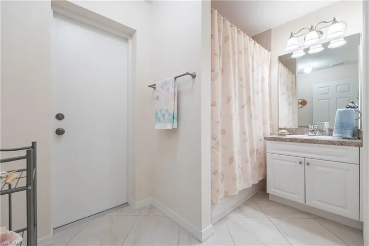 Bathroom featuring a single vanity with an integrated sink, a light-colored countertop, and white cabinetry