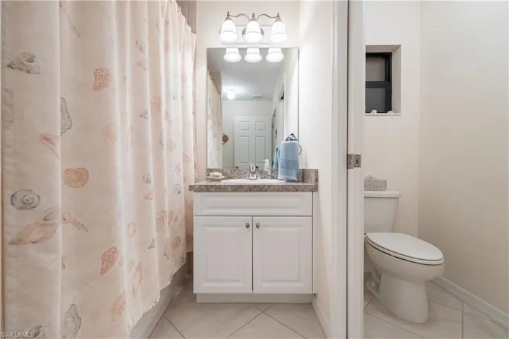 Bathroom featuring a white vanity with cabinet storage, a light-toned countertop, and a four-bulb vanity light fixture