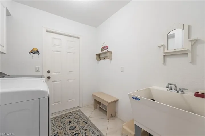 Utility room featuring a built-in utility sink, white paneled door, and tile flooring
