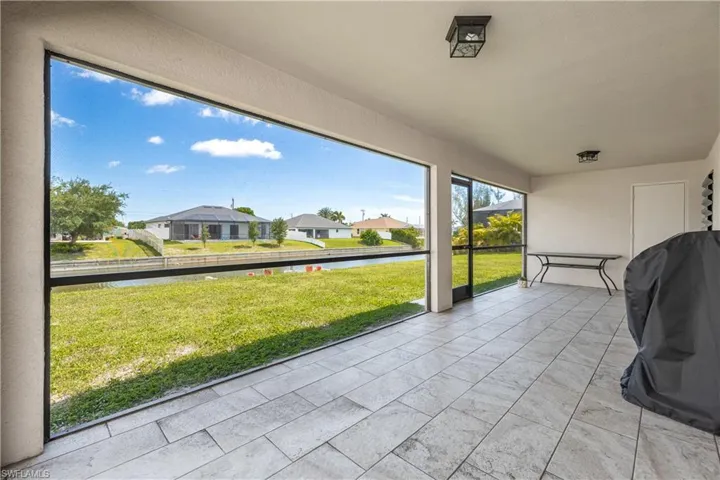 Screened outdoor living area featuring large format tile flooring and two ceiling-mounted light fixtures