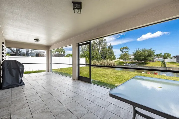 Spacious screened lanai featuring large format tile flooring and two ceiling-mounted light fixtures