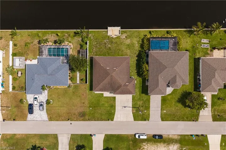 Waterfront property featuring a screened-in pool, private boat dock, and paved driveway
