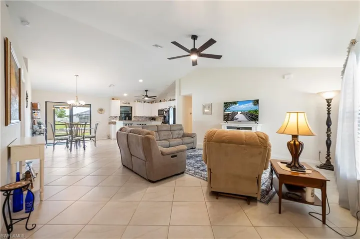 Expansive living area featuring light tile flooring and vaulted ceilings